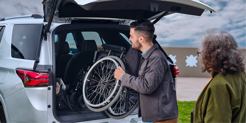 man putting wheel chair in trunk of chevy Traverse
