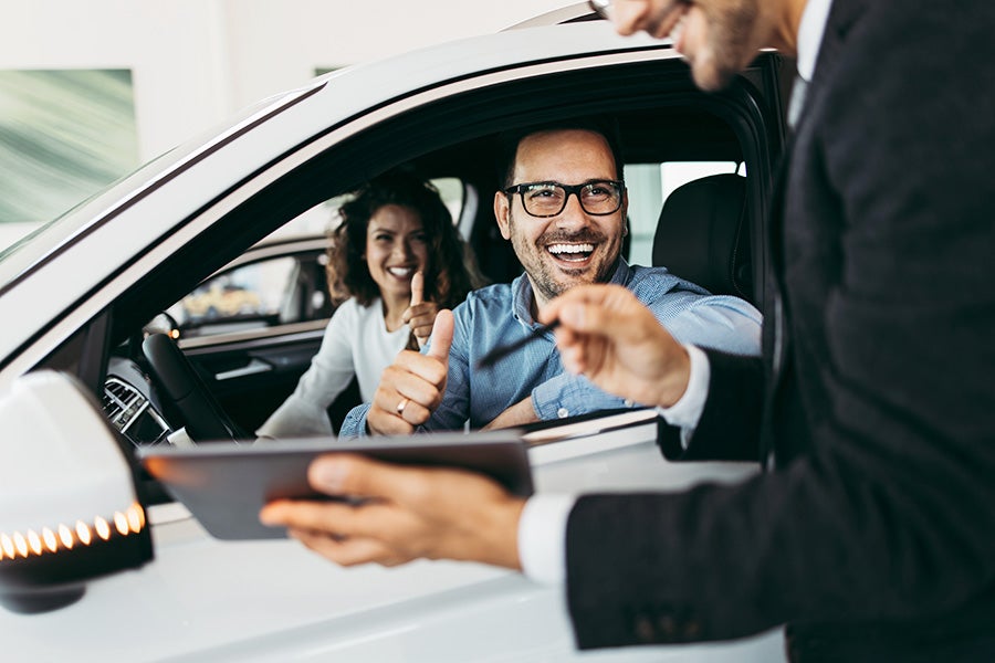 Woman and man sitting in a car at a Chevrolet dealership