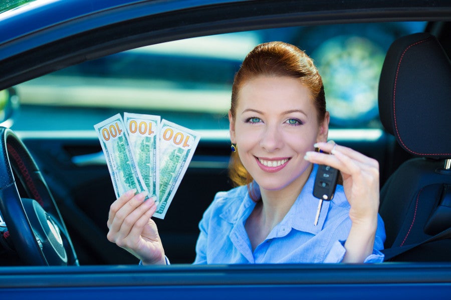Woman sitting in a car, holding cash and car keys